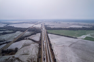 Aerial view of highway in Oklahoma after snow storm with traffic. Trucks and cars are going on interstate along fields.