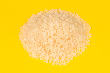 A bunch of rice on a yellow background. Raw rice. Cereals for cooking.