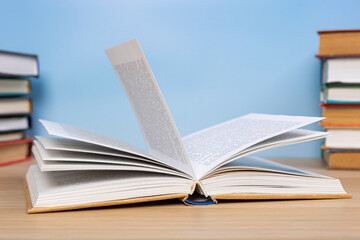Composition with vintage old hardback books, diary and open book whith old pages on wooden table and blue background. Books stacking. Back to school. Copy Space. Education background.