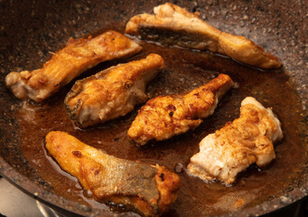 The fish is fried in a frying pan in oil. Close-up.