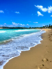Idyllic Carribean white sand beach with blue water and white sea foam
