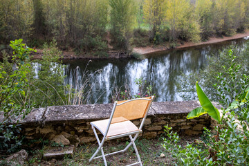 Fototapeta na wymiar Empty garden orange chair at the edge of a river in home outdoor