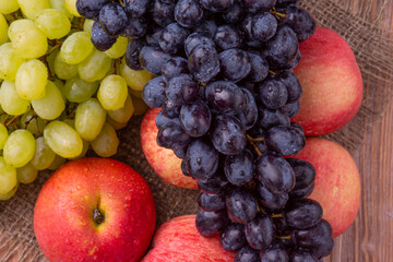 Fresh grapes with red apples on a wooden background