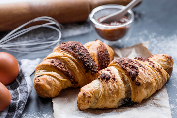 Delicious freshly baked croissants with chocolate on a dark background. French breakfast. Delicious pastries close-up. The context of a bakery with delicious bread. Confectionery products.