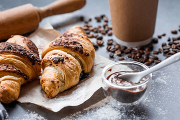 Delicious freshly baked croissants with chocolate and coffee on a dark background. French breakfast. Delicious pastries close-up. The context of a bakery with delicious bread. Confectionery products.