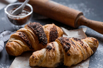 Delicious freshly baked croissants with chocolate on a dark background. French breakfast. Delicious pastries close-up. The context of a bakery with delicious bread. Confectionery products.