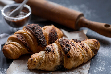 Delicious freshly baked croissants with chocolate on a dark background. French breakfast. Delicious pastries close-up. The context of a bakery with delicious bread. Confectionery products.