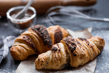 Delicious freshly baked croissants with chocolate on a dark background. French breakfast. Delicious pastries close-up. The context of a bakery with delicious bread. Confectionery products.