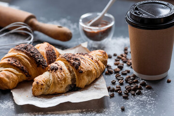 Delicious freshly baked croissants with chocolate and coffee on a dark background. French breakfast. Delicious pastries close-up. The context of a bakery with delicious bread. Confectionery products.