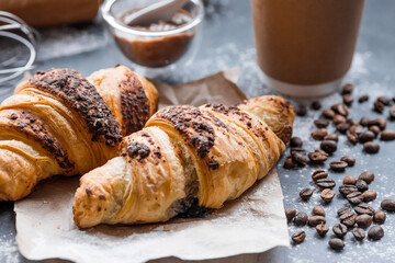 Delicious freshly baked croissants with chocolate and coffee on a dark background. French breakfast. Delicious pastries close-up. The context of a bakery with delicious bread. Confectionery products.