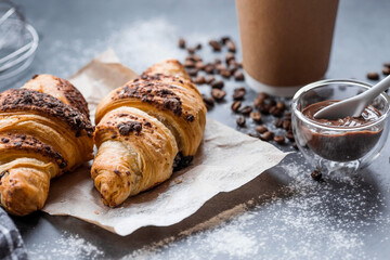 Delicious freshly baked croissants with chocolate and coffee on a dark background. French breakfast. Delicious pastries close-up. The context of a bakery with delicious bread. Confectionery products.