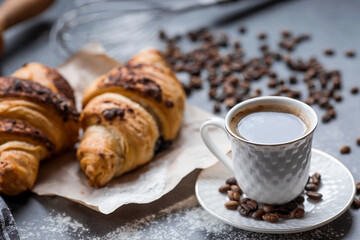 Delicious freshly baked croissants with chocolate and coffee on a dark background. French breakfast. Delicious pastries close-up. The context of a bakery with delicious bread. Confectionery products.