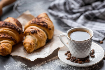 Delicious freshly baked croissants with chocolate and coffee on a dark background. French breakfast. Delicious pastries close-up. The context of a bakery with delicious bread. Confectionery products.