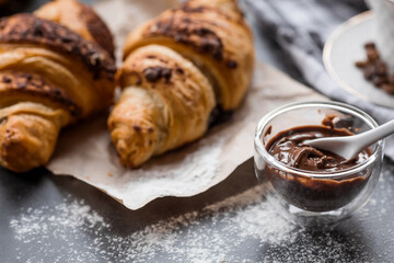 Delicious freshly baked croissants with chocolate on a dark background. French breakfast. Delicious pastries close-up. The context of a bakery with delicious bread. Confectionery products.