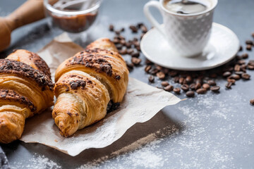 Delicious freshly baked croissants with chocolate and coffee on a dark background. French breakfast. Delicious pastries close-up. The context of a bakery with delicious bread. Confectionery products.
