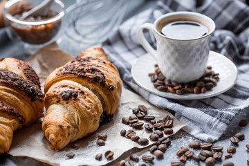 Delicious freshly baked croissants with chocolate and coffee on a dark background. French breakfast. Delicious pastries close-up. The context of a bakery with delicious bread. Confectionery products.