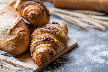 Delicious freshly baked croissants with chocolate on a dark background. French breakfast. Delicious pastries close-up. The context of a bakery with delicious bread. Confectionery products.