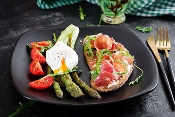 Keto breakfast. Fried asparagus with poached egg and toast with prosciutto or jamon. Ketogenic diet. Healthy food.