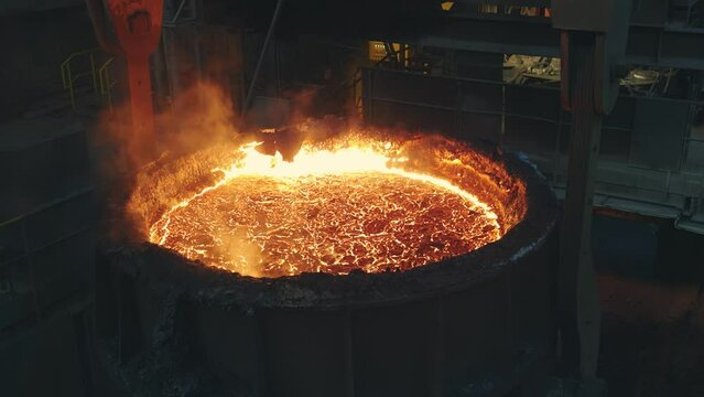 Steel mill ladle and overhead cranes. Crane moving ladle full of hot liquid steel. Transportation of raw material.