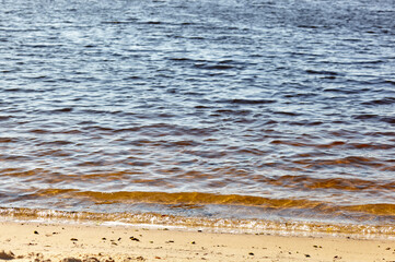 Water's edge on the shore. Wave of blue sea on sandy beach. Beautiful background with water ripples on the beach