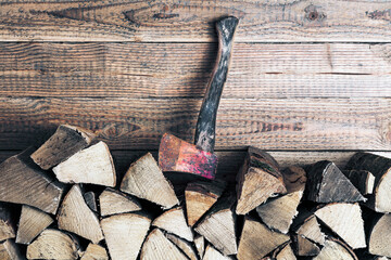 Brennholzstapel mit Axt vor Holzwand