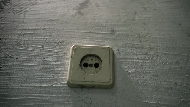 An old electrical socket on a dirty uneven wall. Close-up, smooth camera movement