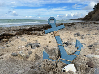 blauer Anker  aus Holz am Strand