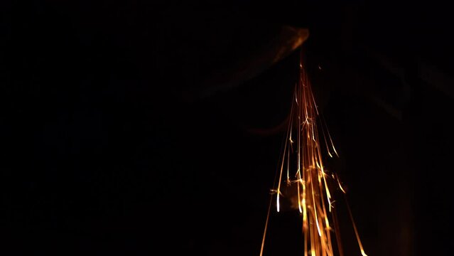 An ax is sharpened on an abrasive wheel of a grinder in the dark with sparks close-up. Bright yellow sparks in the dark