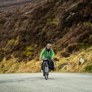 traveler man on bicycle loaded with bags going up hill