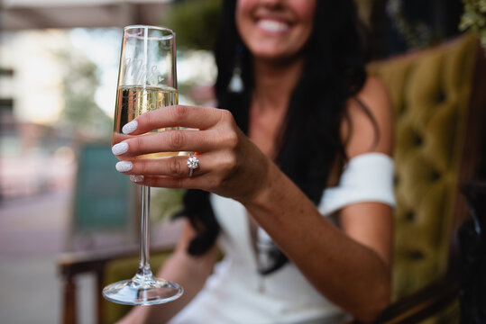 closeup of engagement ring on bride holding champagne