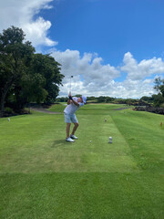 Golfer hitting field with club during summer vacation