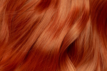 Naklejka premium Red hair close-up as a background. Women's long orange hair. Beautifully styled wavy shiny curls. Hair coloring bright shades. Hairdressing procedures, extension.