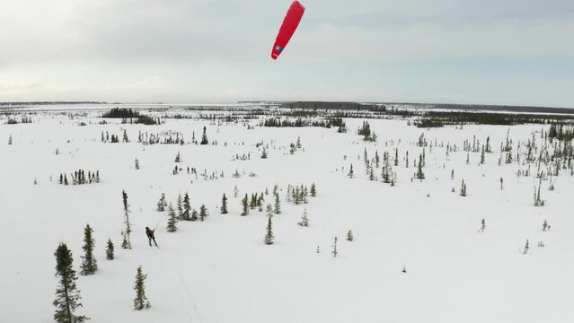 Drone footage of a skier para-skiing with a parachute on a windy winter day in Kenai, Alaska.