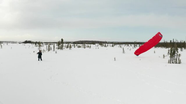 Drone footage of a skier para-skiing with a parachute on a windy winter day in Kenai, Alaska.