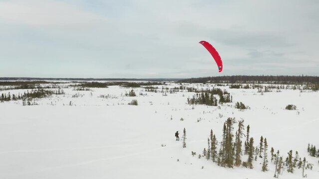 Drone footage of a skier para-skiing with a parachute on a windy winter day in Kenai, Alaska.