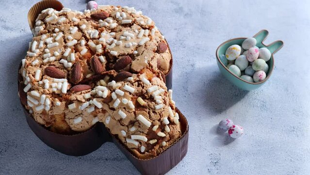  Colomba pasquale-Italian Easter cake on the kitchen table. Easter cake in the shape of a dove with almonds and orange peel. Traditional Italian pastries. paschal eggs in a bowl in the form of a rabbi