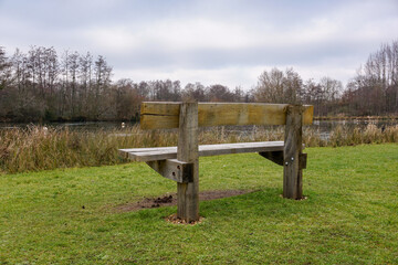 Empty park bench facing lake in parkland. solitude and loneliness concept 