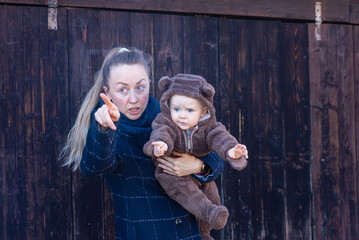 Portrait of young woman holding baby in her hands and showing him something. Mother and son.