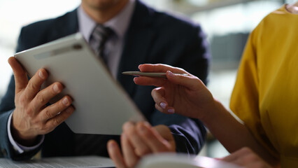 Business colleagues studying information on digital tablet in office closeup. Remote work with...