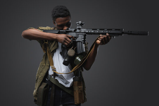 Studio shot of somali buccaneer of african ethnic aiming rifle isolated on gray.