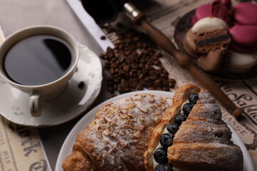 Turkish coffee pot, macaroons, croissants with blueberries and coffee on table