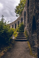 Vertical shot of a historic stone wall and green trees near Oban Bay, Scotland