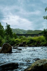 Fototapeta na wymiar Vertical shot of the rocky Glenfinnan Viaduct near the green mountains in Scotland