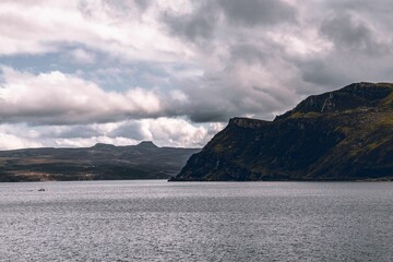 Fototapeta na wymiar Beautiful shot of the historic Isle of Skye cliff over the water under a cloudy sky in Scotland
