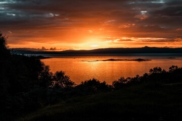 Fototapeta na wymiar Beautiful shot of a bright orange sunset sky over the water in Isle of Skye, Scotland