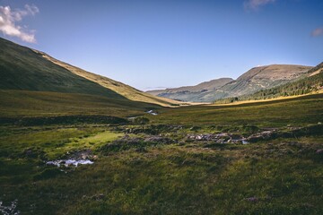 Obraz premium Wide horizontal shot of a landscape in Ilse of Skye, Scotland, with a small waterfall in the middle