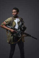 Shot of black soldier in post apocalyptic setting dressed in uniform and holding rifle.