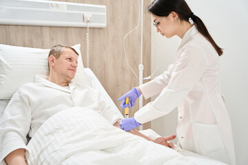 Male getting venous catheter in the vein for blood infusion in medicine center