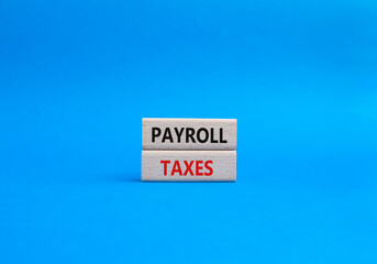 Payroll taxes symbol. Concept word Payroll taxes on wooden blocks. Beautiful blue background. Businessman hand. Business and Payroll taxes concept. Copy space