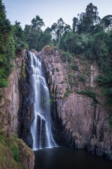 Vertical shot of a waterfall surrounded by trees in a daylight